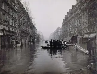 Image de la Crue de 1910. Prise de vue d'un boulevard. On y voit des personnes sur une barque pour traverser la rue.